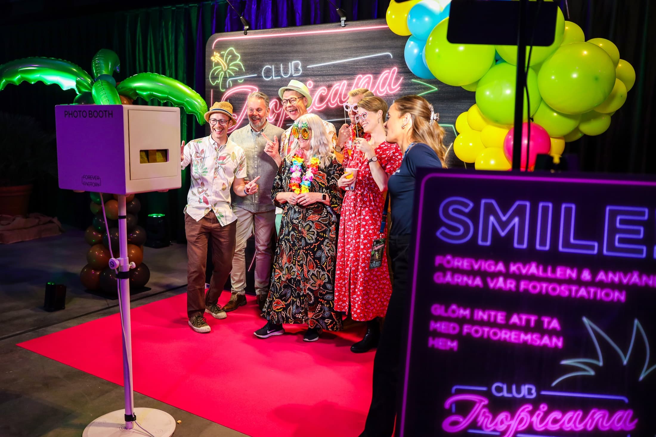 Gäster vid fotobås och Club Tropicana-dekor.